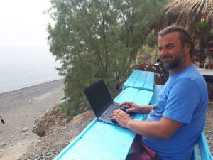 marek pracuje na komputerze na plaży koszty życia na krecie